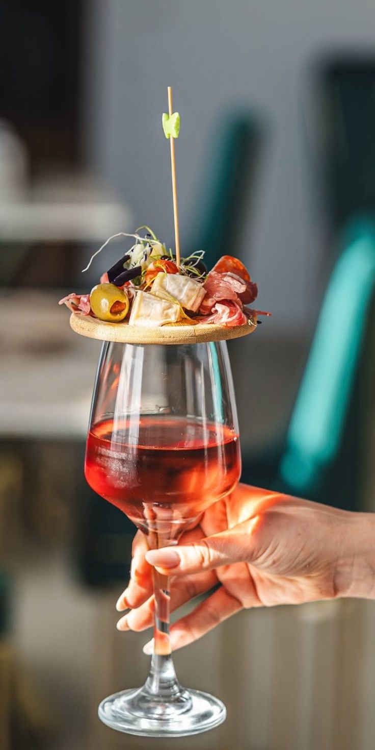 A mini platter of prosciutto, salami, cheeses and olives beside a glass of wine