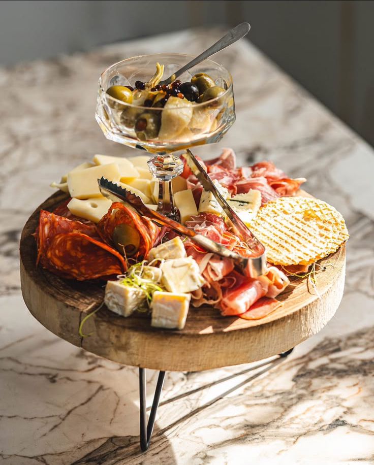 A platter of assorted cheeses, prosciutto, salami and olives