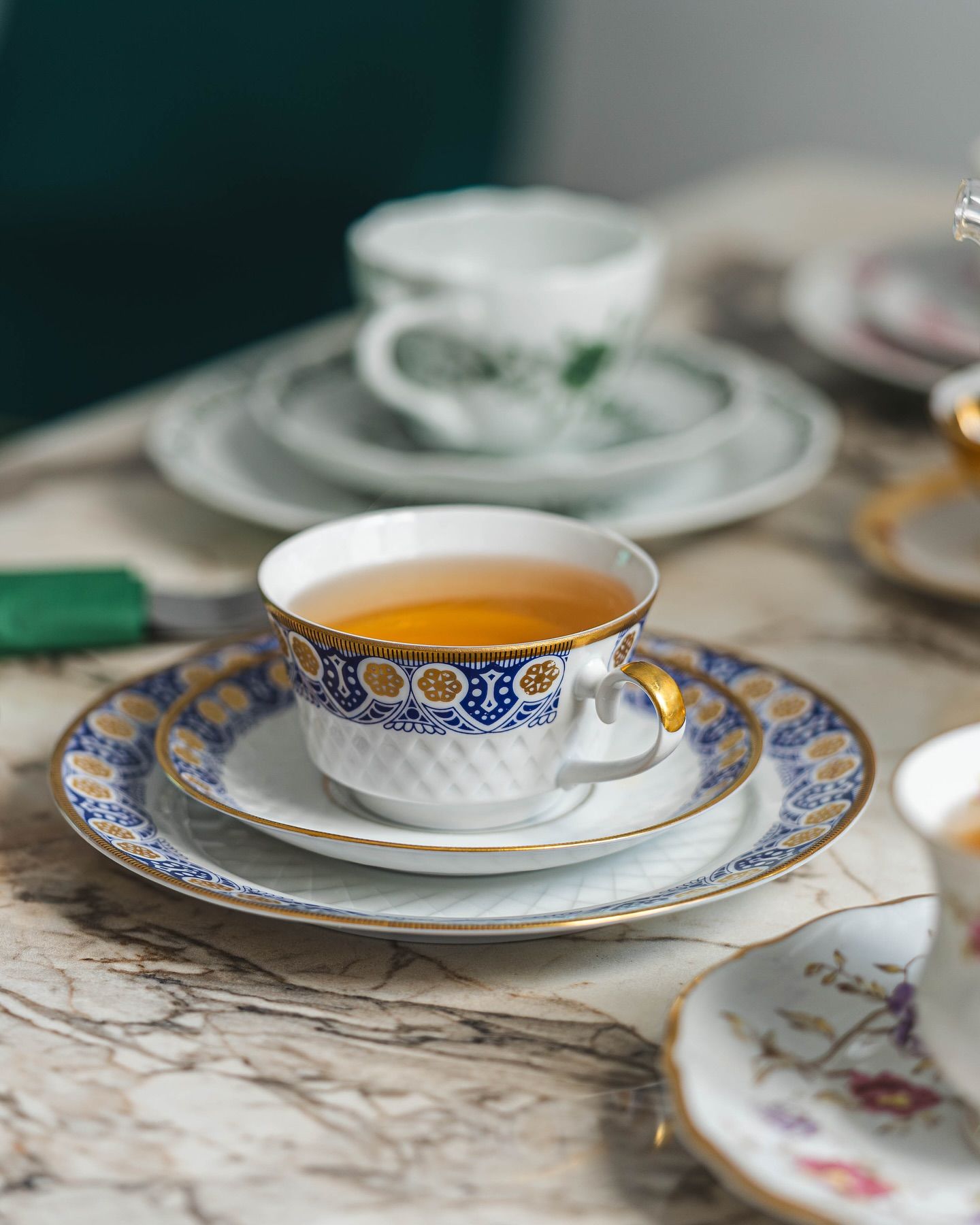A teapot and cups on a table beside the garden windows